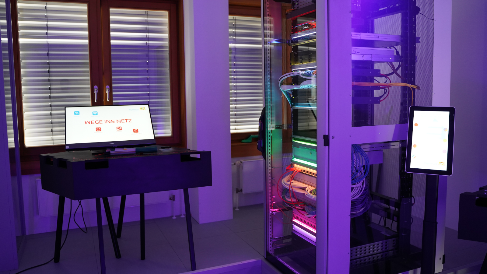 links wird ein All-in-One-PC gezeigt, an dem ausführliche Infos zum Thema Wege ins Netz abgerufen werden können, rechts im Bild ein, mit farbigen LEDs beleuchteter Serverschrank.